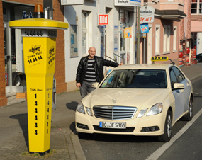 Taxifahrer neben Fahrzeug hinter Rufs�ule